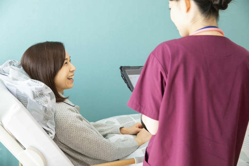看護師と話すベッドに寝ている女性