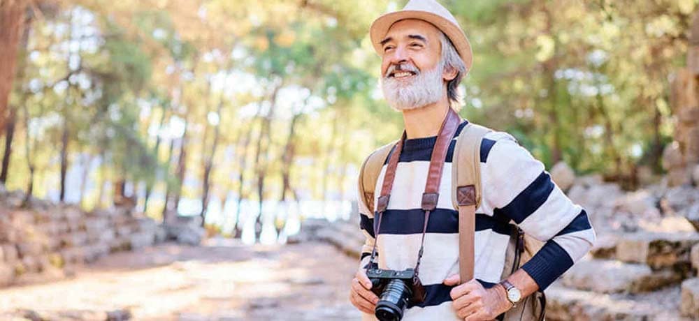 一眼レフカメラを首から下げている初老の男性の写真