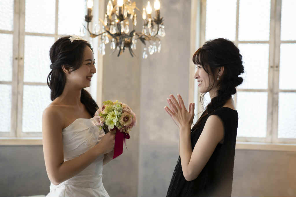 ウェディングドレス姿の新婦と向かい合って祝福する女性の写真